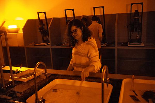 Photography students in a dark room developing photographs